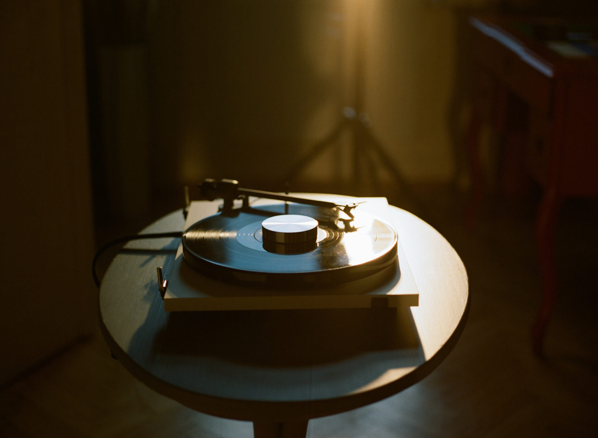 Record-Puck-E-Silver-Lifestyle-E1 Record Puck E laying on a Record on the E1 Record Player wich is placed on a wooden table with sunset behind